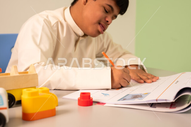 Expressions of focus and enjoyment, the concept of interest in hobbies, having fun, developing mental and intellectual skills in Saudi kindergartens, a Saudi boy with Down syndrome playing with blocks.