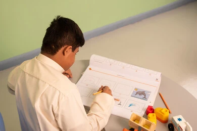 Developing mental and intellectual skills in Saudi kindergartens, expressions of happiness and joy, a Saudi boy with Down syndrome playing with blocks, having fun, the concept of caring for hobbies