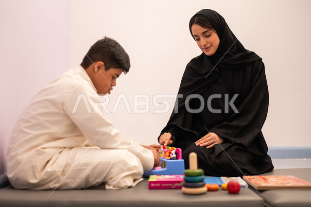 ايماءات التركيز والاندماج  ،تنمية المهارات الذهنيه والفكريه في الروضات السعودية ،  مفهوم التعلم عن طريق اللعب،وسائل ايضاح ترفيفهيه للتعليم ،ولد عربي سعودي مصاب بمتلازمه داون يقوم باللعب بلعبه الكروت التعليميه برفقه معلمته ، قضاء اوقات ممتعه