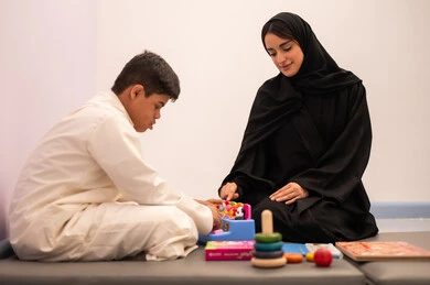 ايماءات التركيز والاندماج  ،تنمية المهارات الذهنيه والفكريه في الروضات السعودية ،  مفهوم التعلم عن طريق اللعب،وسائل ايضاح ترفيفهيه للتعليم ،ولد عربي سعودي مصاب بمتلازمه داون يقوم باللعب بلعبه الكروت التعليميه برفقه معلمته ، قضاء اوقات ممتعه