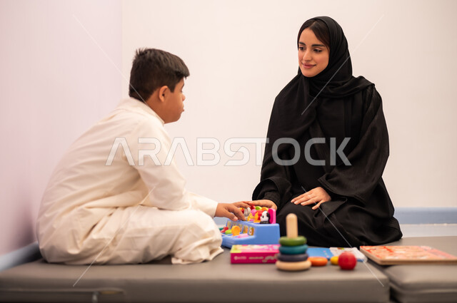 تنمية المهارات الذهنيه والفكريه في الروضات السعودية ،  مفهوم التعلم عن طريق اللعب،وسائل ايضاح ترفيفهيه للتعليم ،ايماءات التركيز والاندماج  ،ولد عربي سعودي مصاب بمتلازمه داون يقوم باللعب بلعبه الكروت التعليميه برفقه معلمته ، قضاء اوقات ممتعه