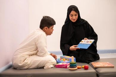 مفهوم التعلم عن طريق اللعب،وسائل ايضاح ترفيفهيه للتعليم ،ايماءات التركيز والاندماج  ،تنمية المهارات الذهنيه والفكريه في الروضات السعودية ،ولد عربي سعودي مصاب بمتلازمه داون يقوم باللعب بلعبه الكروت التعليميه برفقه معلمته ، قضاء اوقات ممتعه