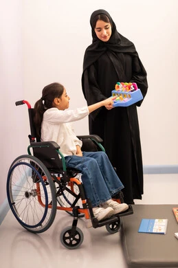 تعزيز النشاط الذهني، قضاء اوقات ممتعه ،تنمية المهارات الذهنيه والفكريه في الروضات السعودية ، بنت عربيه سعوديه ترتدي الزي الكاجوال تجلس على كرسي متحرك، تقوم باللعب بلعبه الكروت المطابقه برفقه معلمتها ، تعابير السرور والسعاده