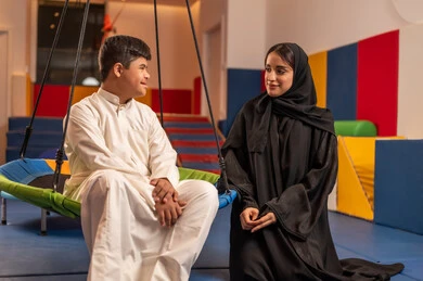 اوقات التسلية و الترفيه ،ايماءات السرور والسعاده ، الاستمتاع باللعب في العطلة الصيفية ،قضاء اوقات رائعة في مدينة الملاهي ،ولد سعودي مصاب بمتلازمة داون في مدينة الألعاب برفقه والدته، يلعب لعبة المراجيح المسلية