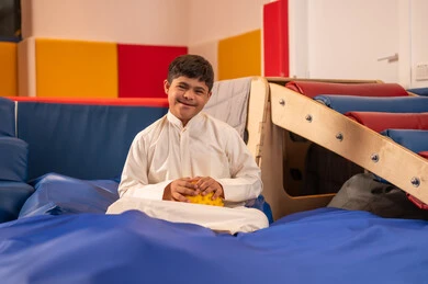 ولد سعودي مصاب بمتلازمة داون في مدينة الألعاب ، يلعب لعبة الزحليقه المسلية يرفع يده بعلامه النصر ،ايماءات السرور والسعاده ، قضاء اوقات رائعة في مدينة الملاهي ، اوقات التسلية و الترفيه ،الاستمتاع باللعب في العطلة الصيفية