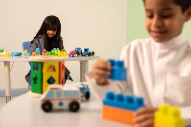 بنت عربية خليجية عمانية ترتدي الزي الكاجوال تقوم بالمهارات والانشطه،تنمية المهارات الذهنية والفكرية ،أداء الكثير من الأنشطة الممتعة ، الاعتناء بمهارات الاطفال، رياض الأطفال والحاضنات، ولد سعودي يلعب بالمكعبات الملونه