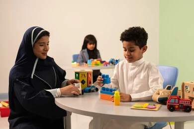 ولد عربي خليجي عماني يرتدي الزي العماني التقليدي يقوم بالمهارات والانشطه برفقه معلمته ، معلمة عربية عمانيه لرياض أطفال تختص بالاعتناء بالاطفال، رياض الأطفال والحاضنات،أداء الكثير من الأنشطة الممتعة ،بنت عمانية تلعب بالالعاب البلاستيكيه