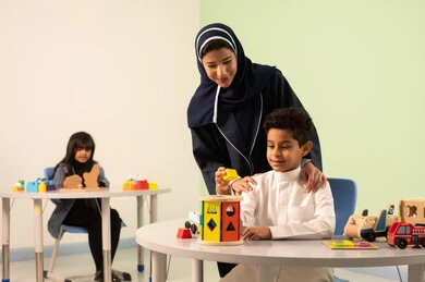 رياض الأطفال والحاضنات،معلمة عربية عمانيه لرياض أطفال تختص بالاعتناء بالاطفال،أداء الكثير من الأنشطة الممتعة ، ولد عربي خليجي عماني يرتدي الزي العماني التقليدي يقوم بالمهارات والانشطه برفقه معلمته ، بنت عمانية تلعب بالالعاب البلاستيكيه