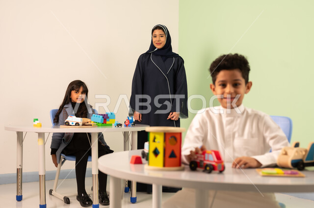 Fun in the summer vacation, an Omani Arab teacher for kindergarten specializing in caring for children, performing many enjoyable activities, kindergartens and nurseries, two Omani children engaging in various activities, spending wonderful times at the amusement park, games for entertainment and leisure.