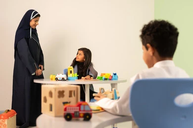 An Omani Arabic teacher for kindergarten specializes in taking care of children, performing many fun activities, kindergartens and nurseries, two Omani children engaging in various activities, spending wonderful times at the amusement park, games for fun and entertainment, enjoyment during the summer vacation.