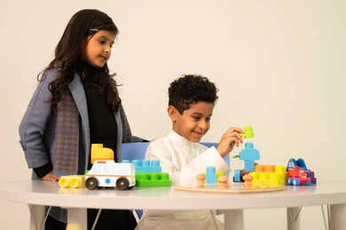 Developing mental and intellectual skills, a group of collective activities, two Saudi children sitting in kindergartens and nurseries, engaging in many fun and different activities, enjoying recreational games.