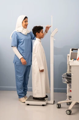 The concept of health and fitness, excess weight and obesity, the accumulation of calories, an Arab Saudi Gulf boy with a full body suffering from obesity, an Omani nurse using a scale to measure weight, suffering from health problems.