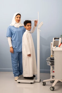 Overweight and obesity, accumulation of calories, the concept of health and fitness awareness, an Arab Saudi Gulf boy with a full body suffering from obesity, an Omani nurse using a scale to measure weight, suffering from health problems.