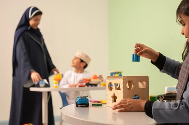 An Omani boy wearing a dishdasha and kumma in kindergartens and nurseries engages in many fun and different activities. An Arab Omani teacher for kindergarten specializes in taking care of children, offering a variety of individual activities.