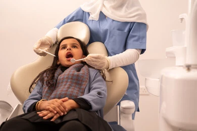 مفهوم الطب والرعاية الصحية، استخدام المعدات اللازمة لجراحة الاسنان ، طبيبة ترتدي القفازات تقوم بفحص أسنان المريض، بنت عربية خليجية عمانية ترتدي الزي الكاجوال تجلس على كرسي العلاج في العيادة السنية، تقديم الخدمات الطبية للمرضى ، إجراء الفحوصات الدورية للعناية بالصحة الفموية