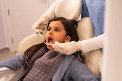 طبيبة ترتدي القفازات تقوم بفحص أسنان المريض، استخدام المعدات اللازمة لجراحة الاسنان ، مفهوم الطب والرعاية الصحية، بنت عربية خليجية عمانية ترتدي الزي الكاجوال تجلس على كرسي العلاج في العيادة السنية، تقديم الخدمات الطبية للمرضى ، إجراء الفحوصات الدورية للعناية بالصحة الفموية