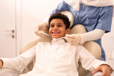 تقديم الخدمات الطبية للمرضى ،استخدام المعدات اللازمة لجراحة الاسنان ، مفهوم الطب والرعاية الصحية، طبيبة ترتدي القفازات تقوم بفحص أسنان المريض، ولد عربي خليجي عماني يرتدي الزي العماني التقليدي يجلس على كرسي العلاج في العيادة السنية،  إجراء الفحوصات الدورية للعناية بالصحة الفموية