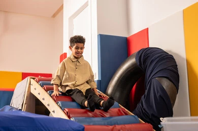 الاستمتاع بالالعاب الترفيهية، مدينه الالعاب في سلطنة عمان، مفهوم اللهو واللعب، اجواء صيفية ممتعة،  ولد عربي خليجي عماني يرتدي الزي الكاجوال  مستمتع بالتزحلق على الزحليقة ، العاب التسلية والمتعه