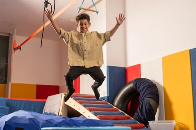 مدينه الالعاب في سلطنة عمان،مفهوم اللهو واللعب، اجواء صيفية ممتعة، القفز عالياً بايماءات السعادة والسرور، ولد عربي خليجي عماني يرتدي الزي الكاجوال  مستمتع باللعب امام الزحليقة ، الاستمتاع بالالعاب الترفيهية، العاب التسلية والمتعه