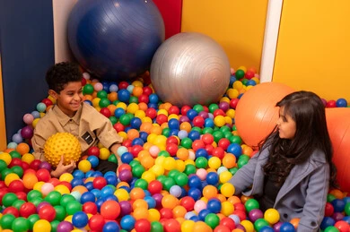 طفلان سعوديان يرتديان الزي الكاجوال في مدينة الألعاب ، يلعبان في حوض الكور البلاستيكية ، طفلان عمانيان يقضيان اوقات رائعة في مدينة الملاهي ، العاب التسلية و الترفيه ، المتعه في العطلة الصيفية