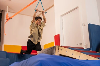 تنمية المهارات الحركية للأطفال، ولد عربي خليجي سعودي يرتدي الزي الكاجوال يستمتع باللعب في مدينة الألعاب ، يتسلق على الألعاب الخشبية المجهزة بالحبال والعوارض الملونة، قضاء أوقات ممتعة مليئة بالنشاط والحركة، مفهوم المرح والترفيه