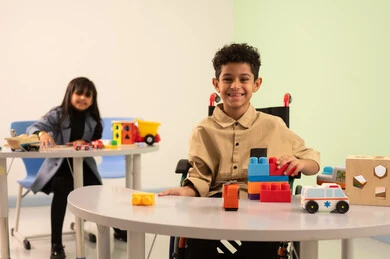 أداء الكثير من الأنشطة الممتعة لذوي الهمم، تنمية المهارات الذهنية والفكرية ، الاعتناء بالاطفال ذوي الاحتياجات الخاصة، رياض الأطفال والحاضنات، بنت عربية خليجية عمانية ترتدي الزي الكاجوال تقوم بالمهارات والانشطه، ولد سعودي يلعب بالمكعبات الملونه