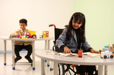 رياض الأطفال والحاضنات، أداء الكثير من الأنشطة الممتعة لذوي الهمم، الاعتناء بالاطفال ذوي الاحتياجات الخاصة،  بنت عربية خليجية عمانية ترتدي الزي الكاجوال تقوم بالمهارات والانشطه، ولد سعودي يلعب بالالعاب البلاستيكيه الملونه