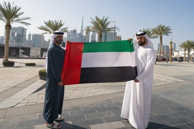 الإحتفال باليوم الوطني الإماراتي، يوم استقلال الإمارات، رجلان عربيان خليجيان اماراتيان يرتديان الكندورة والغترة يحملان علم الإمارات العربية المتحدة، الاعتزاز والفخر بإنجازات البلاد، هوية اليوم الوطني الاماراتي 51، الطول الكامل للجسم
