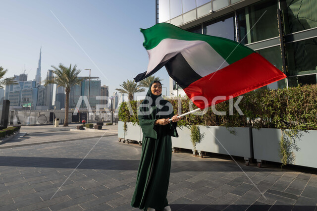 ذكرى تأسيس الاتحاد 2 ديسمبر،استذكار اليوم الوطني الاماراتي 1971، إمراة عربية خليجية إماراتية ترتدي الحجاب والعباءة تمسك بيدها علم الإمارات العربية المتحدة ، يوم العلم 3 نوفمبر، حب الوطن والاعتزاز به، التجول في الشوارع بايماءات السعادة والفخر والاعتزاز