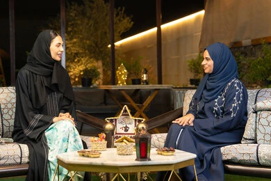 اضاءة وزينة رمضانية، حسن الاستقبال في شهر رمضان المبارك، امراتان سعوديتان تجلسان بالجلسة الخارجية في احدى شاليهات الامارات، صديقتان عربيتان خليجيتان اماراتيتان ترتديان العباءة والحجاب تجلسان في الهواء الطلق