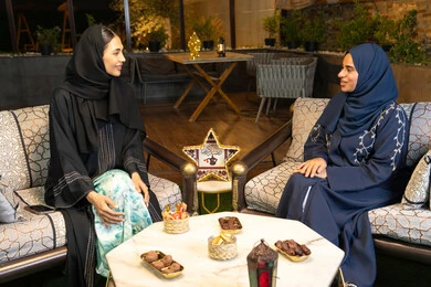 Warm welcome in the holy month of Ramadan, Ramadan lighting and decorations, two Saudi women sitting outdoors in a chalet in the Emirates, two Emirati Gulf Arab friends wearing the abaya and hijab sitting outdoors