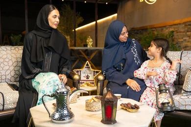 الجلسة الليلة الخارجية في احدى شاليهات الامارات، زينة واضاءة رمضانية، حسن الاستقبال وكرم الضيافة في شهر رمضان المبارك، امراة عربية خليجية اماراتية تجلس في الهواء الطلق مع صديقتها وابنتها، سيدتان سعوديتان تقومان بتبادل الاحاديث والاخبار بتعابير السرور