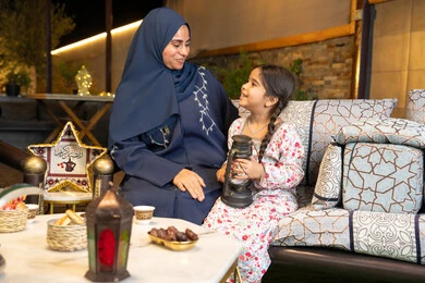 الاحتفال بقدوم شهر الخير، زينة واضاءة شهر رمضان المبارك، الجلسة الليلة الخارجية في احدى شاليهات الامارات،  امراة عربية خليجية اماراتية تجلس في الهواء الطلق، سيدة سعودية تنظر الى ابنتها بايماءات السعادة والسرور