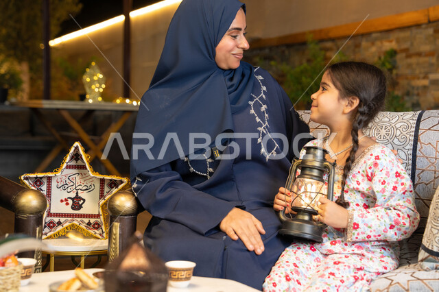 الجلسة الليلة الخارجية في احدى شاليهات الامارات، الاحتفال بقدوم شهر الخير، زينة واضاءة شهر رمضان المبارك، امراة عربية خليجية اماراتية تجلس في الهواء الطلق، سيدة سعودية تنظر الى ابنتها بايماءات السعادة والسرور