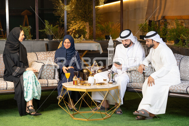 كرم الضيافة وحسن الاستقبال في شهر رمضان المبارك، تبادل الاحاديث والاخبار بتعابير السرور والسعادة، الجلسة الليلة الخارجية في احدى شاليهات الامارات، زينة واضاءة رمضانية، مجموعة من الأصدقاء العرب الخليجيين الاماراتيين يجلسون في الهواء الطلق