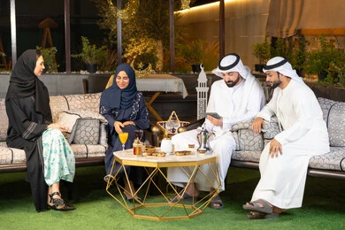 كرم الضيافة وحسن الاستقبال في شهر رمضان المبارك، تبادل الاحاديث والاخبار بتعابير السرور والسعادة، الجلسة الليلة الخارجية في احدى شاليهات الامارات، زينة واضاءة رمضانية، مجموعة من الأصدقاء العرب الخليجيين الاماراتيين يجلسون في الهواء الطلق