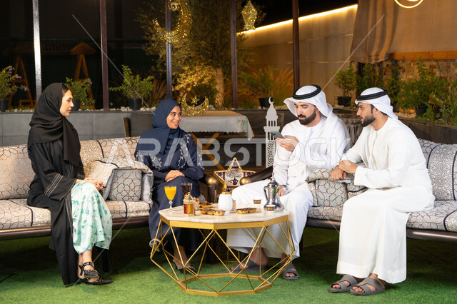 كرم الضيافة وحسن الاستقبال في شهر رمضان المبارك، تبادل الاحاديث والاخبار بتعابير السرور والسعادة، الجلسة الليلة الخارجية في احدى شاليهات الامارات، زينة واضاءة رمضانية، مجموعة من الأصدقاء العرب الخليجيين الاماراتيين يجلسون في الهواء الطلق