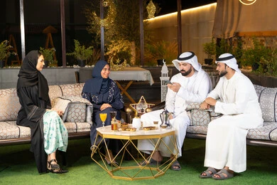 كرم الضيافة وحسن الاستقبال في شهر رمضان المبارك، تبادل الاحاديث والاخبار بتعابير السرور والسعادة، الجلسة الليلة الخارجية في احدى شاليهات الامارات، زينة واضاءة رمضانية، مجموعة من الأصدقاء العرب الخليجيين الاماراتيين يجلسون في الهواء الطلق