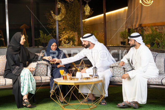 كرم الضيافة وحسن الاستقبال في شهر رمضان المبارك، تبادل الاحاديث والاخبار بتعابير السرور والسعادة، الجلسة الليلة الخارجية في احدى شاليهات الامارات، زينة واضاءة رمضانية، مجموعة من الأصدقاء العرب الخليجيين الاماراتيين يجلسون في الهواء الطلق