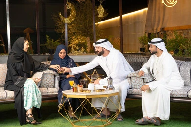 Hospitality and warm welcome in the holy month of Ramadan, exchanging conversations and news with expressions of pleasure and happiness, an outdoor evening gathering in one of the chalets in the Emirates, Ramadan decorations and lighting, a group of Emirati Gulf Arab friends sitting in the open air