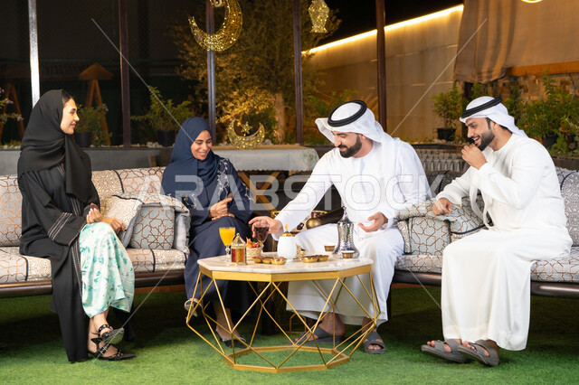 زينة واضاءة رمضانية، الجلسة الليلة الخارجية في احدى شاليهات الامارات، حسن الاستقبال وكرم الضيافة في شهر رمضان المبارك، مجموعة من الأصدقاء العرب الخليجيين الاماراتيين يجلسون في الهواء الطلق، تبادل الاحاديث والاخبار بتعابير السرور والسعادة