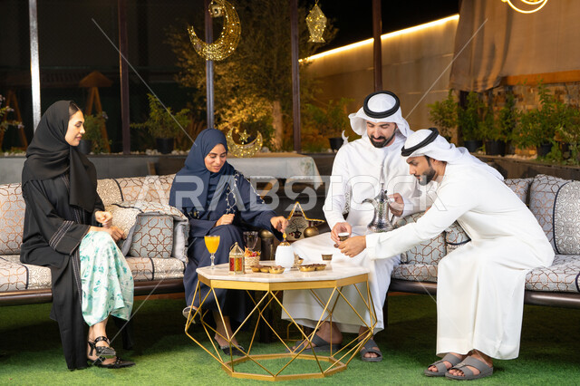 حسن الاستقبال وكرم الضيافة في شهر رمضان المبارك، الجلسة الليلة الخارجية في احدى شاليهات الامارات، زينة واضاءة رمضانية، مجموعة من الأصدقاء العرب الخليجيين الاماراتيين يجلسون في الهواء الطلق، تبادل الاحاديث والاخبار بتعابير السرور والسعادة