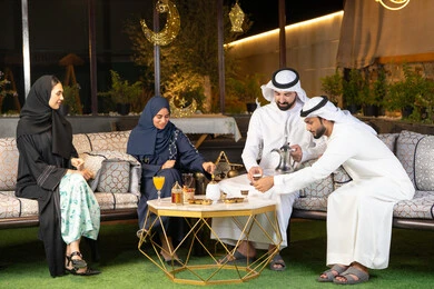حسن الاستقبال وكرم الضيافة في شهر رمضان المبارك، الجلسة الليلة الخارجية في احدى شاليهات الامارات، زينة واضاءة رمضانية، مجموعة من الأصدقاء العرب الخليجيين الاماراتيين يجلسون في الهواء الطلق، تبادل الاحاديث والاخبار بتعابير السرور والسعادة
