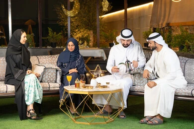 الجلسة الليلة الخارجية في احدى شاليهات الامارات، زينة واضاءة رمضانية، حسن الاستقبال وكرم الضيافة في شهر رمضان المبارك، مجموعة من الأصدقاء العرب الخليجيين الاماراتيين يجلسون في الهواء الطلق، تبادل الاحاديث والاخبار بتعابير السرور والسعادة