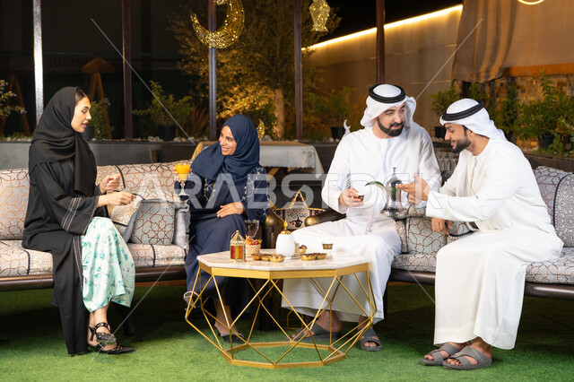 تبادل الاحاديث والاخبار بتعابير السرور والسعادة، زينة واضاءة رمضانية، الجلسة الليلة الخارجية في احدى شاليهات الامارات، حسن الاستقبال وكرم الضيافة في شهر رمضان المبارك، مجموعة من الأصدقاء العرب الخليجيين الاماراتيين يجلسون في الهواء الطلق
