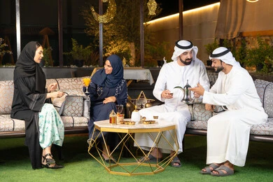 تبادل الاحاديث والاخبار بتعابير السرور والسعادة، زينة واضاءة رمضانية، الجلسة الليلة الخارجية في احدى شاليهات الامارات، حسن الاستقبال وكرم الضيافة في شهر رمضان المبارك، مجموعة من الأصدقاء العرب الخليجيين الاماراتيين يجلسون في الهواء الطلق