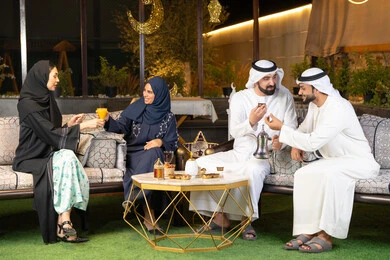 جودة الاستقبال وكرم الضيافة في شهر رمضان المبارك، الجلسة الليلة الخارجية في احدى شاليهات الامارات، زينة واضاءة رمضانية، مجموعة من الأصدقاء العرب الخليجيين الاماراتيين يجلسون في الهواء الطلق، تبادل الاحاديث والاخبار بتعابير السرور والسعادة