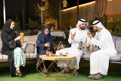 الجلسة الليلة الخارجية في احدى شاليهات الامارات، زينة واضاءة رمضانية، حسن الاستقبال وكرم الضيافة في شهر رمضان المبارك، مجموعة من الأصدقاء العرب الخليجيين الاماراتيين يجلسون في الهواء الطلق، تبادل الاحاديث والاخبار بتعابير السرور والسعادة