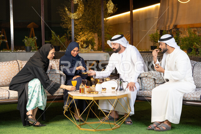 ديكور واضاءة رمضانية، الجلسة الليلة الخارجية في احدى شاليهات الامارات، حسن الاستقبال وكرم الضيافة في شهر رمضان المبارك، مجموعة من الأصدقاء العرب الخليجيين الاماراتيين يجلسون في الهواء الطلق، تبادل الاحاديث والاخبار بتعابير السرور والسعادة