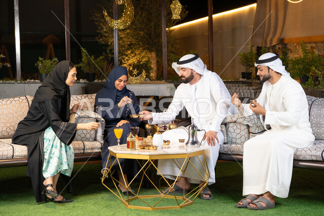 الجلسة الليلة الخارجية في احدى شاليهات الامارات، زينة واضاءة رمضانية، حسن الاستقبال وكرم الضيافة في شهر رمضان المبارك، مجموعة من الأصدقاء العرب الخليجيين الاماراتيين يجلسون في الهواء الطلق، تبادل الاحاديث والاخبار بتعابير السرور والسعادة
